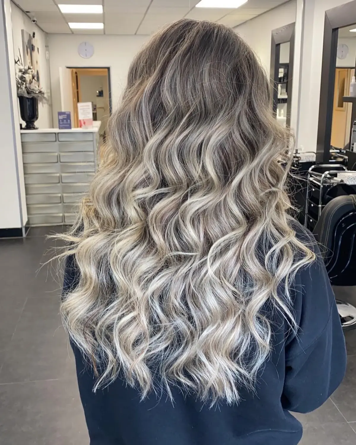 Lang, golvend haar met een blonde balayage, van achteren gezien in de salon