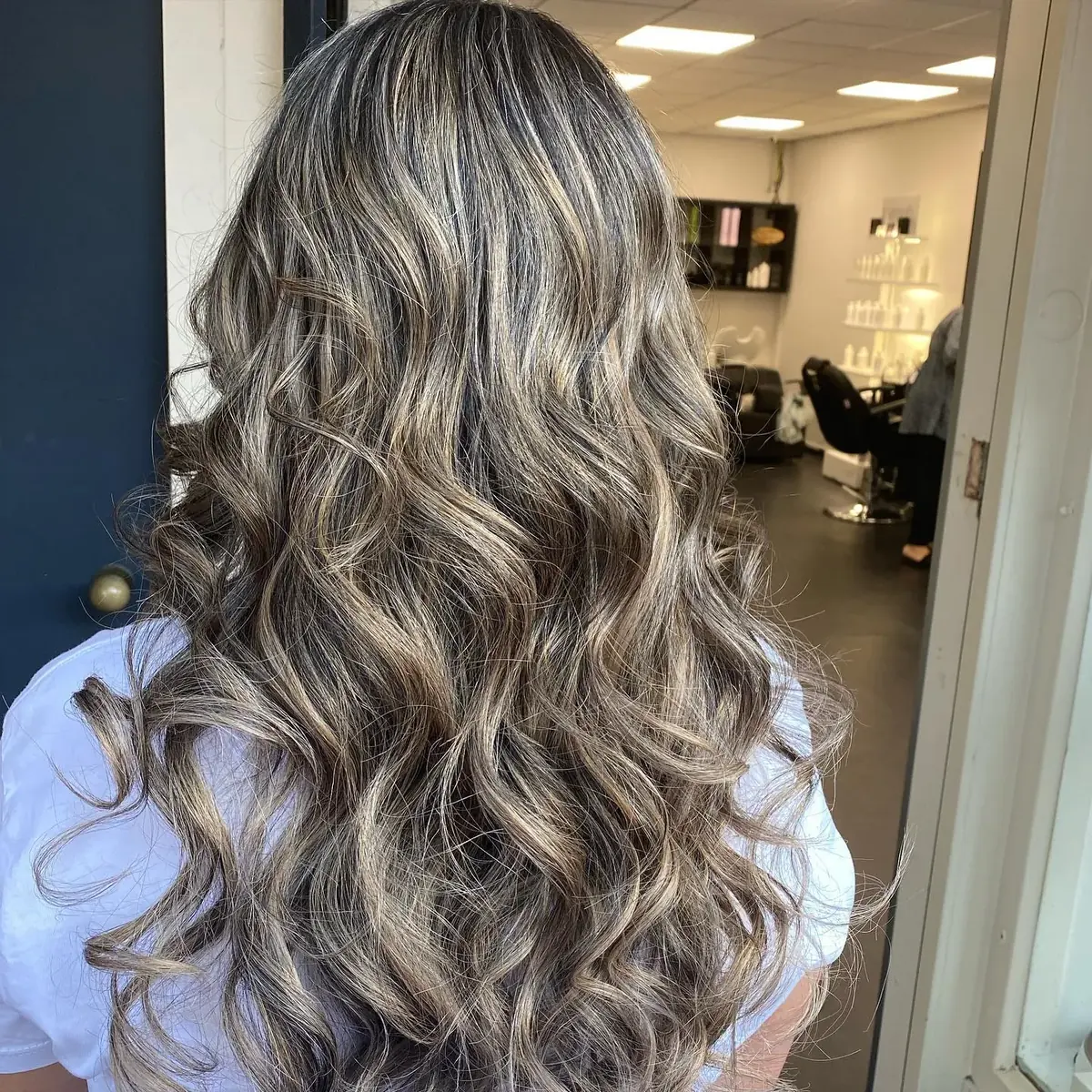 Lang, golvend haar met asblonde highlights, van achteren gezien in de salon