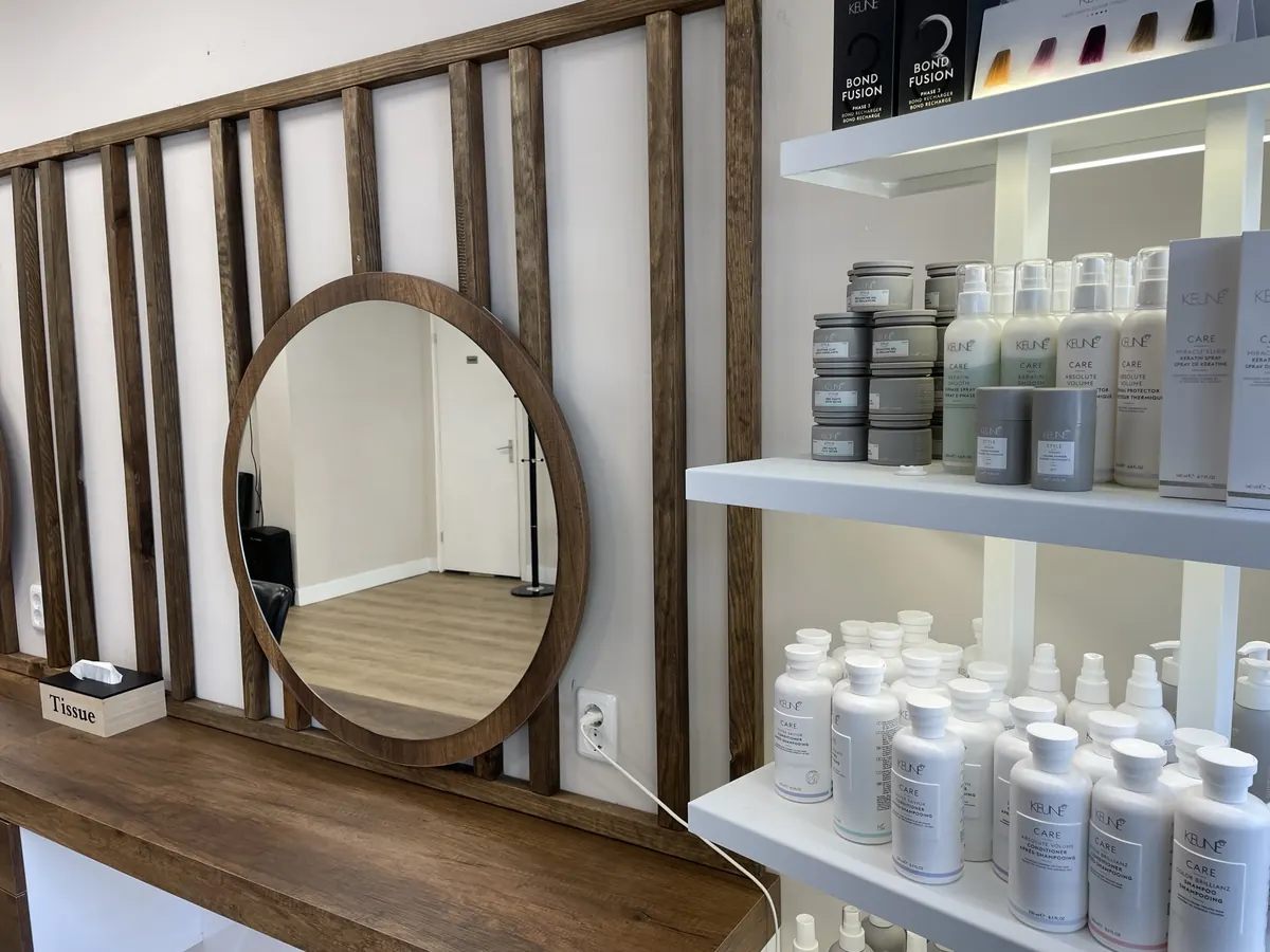Schap met professionele haarproducten naast een ronde spiegel